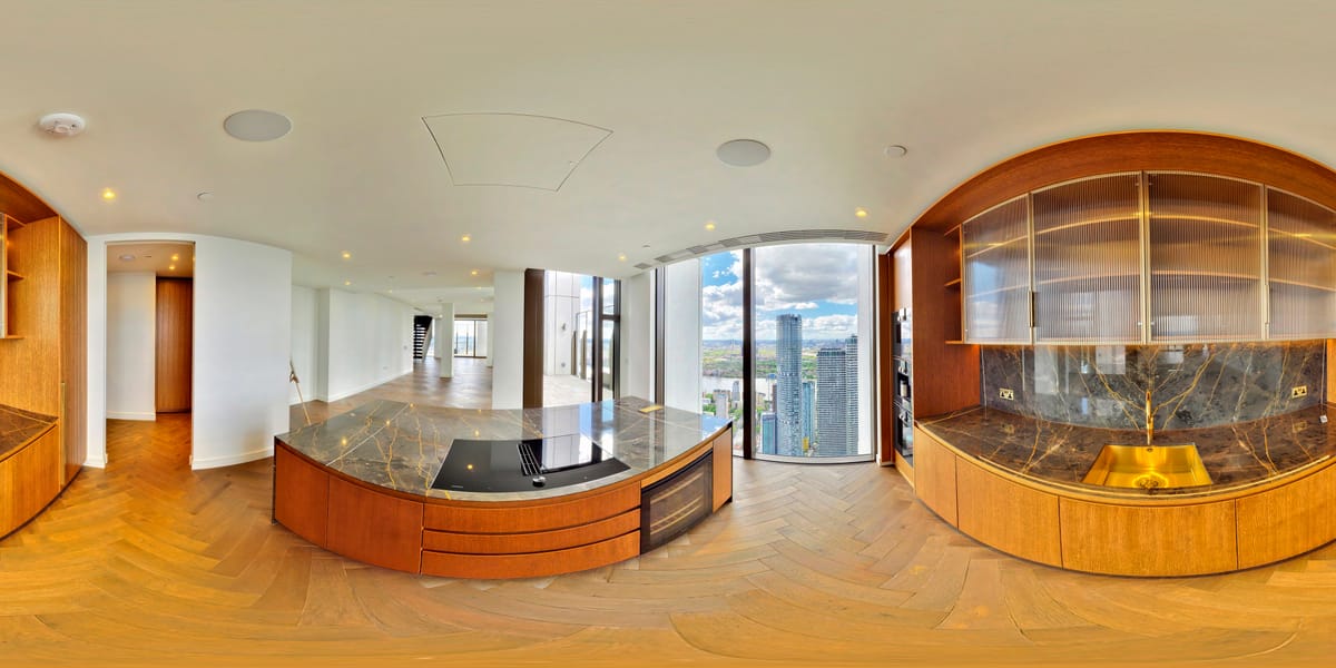 Curved dark marble kitchen island with warm wood cabinetry and city views beyond