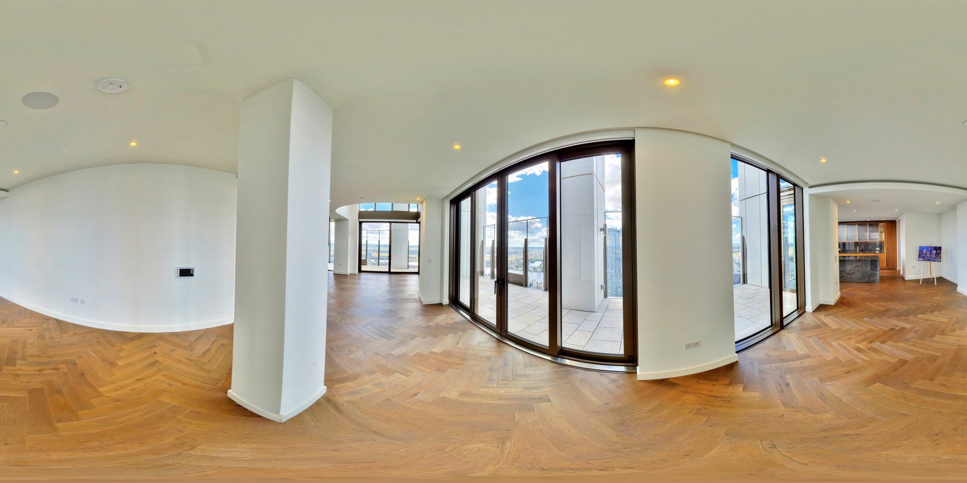 Open plan living space with herringbone parquet floors and floor-to-ceiling glass doors to the terrace